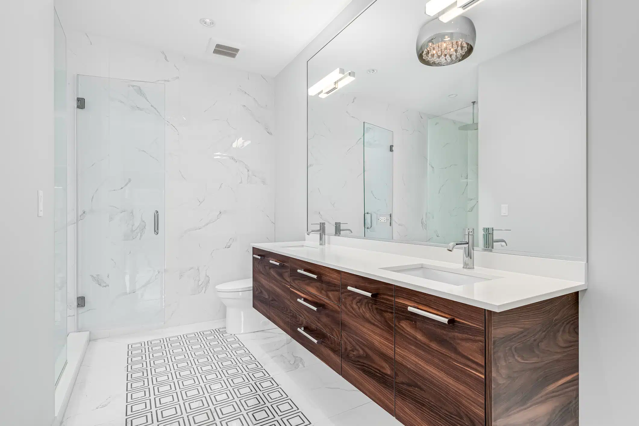 A bathroom with a wood cabinet, marble shower, and pattern tile floor.